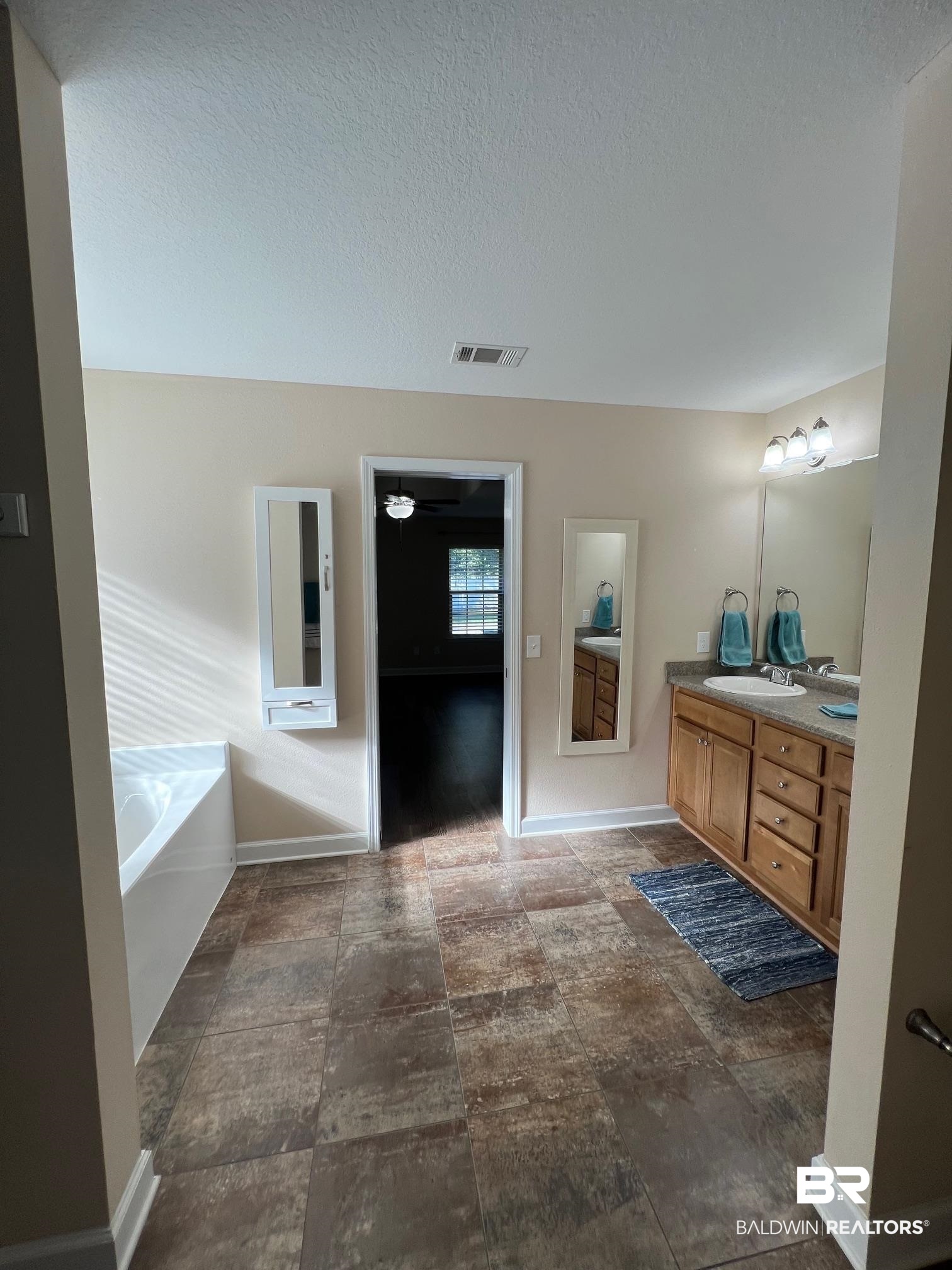 10257 Lyttleton Loop Lillian, AL 36549 - Photo 17 of 31 Full bath with double vanity, a bath, and a textured ceiling