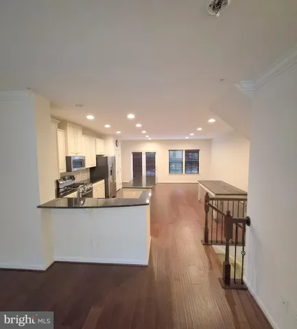 a living room with stainless steel appliances kitchen island granite countertop furniture a desk and chair with wooden floor