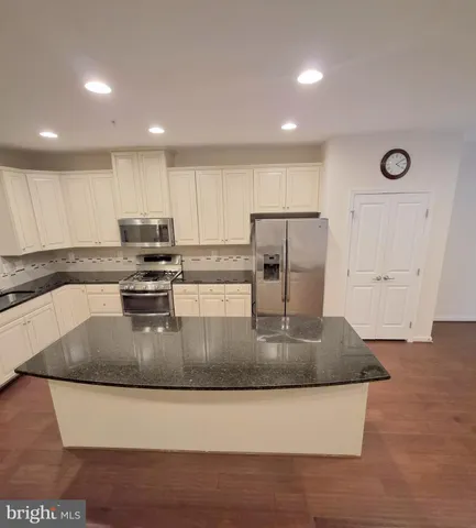 a kitchen with kitchen island a counter top a stove and a refrigerator