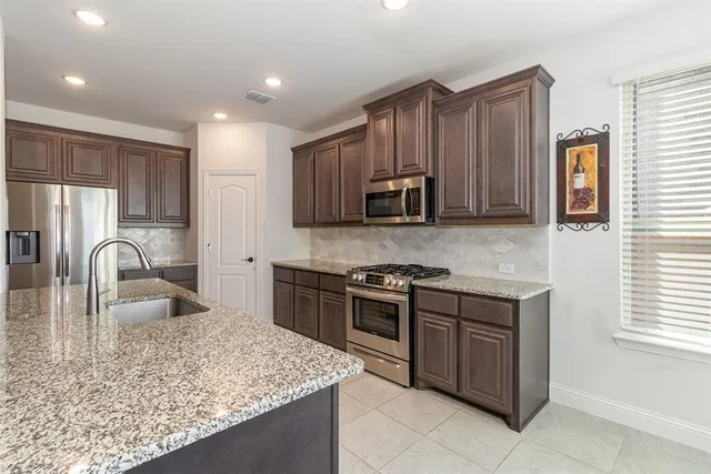 a large kitchen with kitchen island granite countertop a large counter top space appliances and cabinets