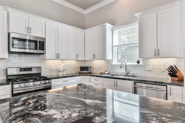a kitchen with stainless steel appliances granite countertop a stove sink microwave and cabinets