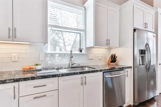 a kitchen with granite countertop a refrigerator sink and cabinets
