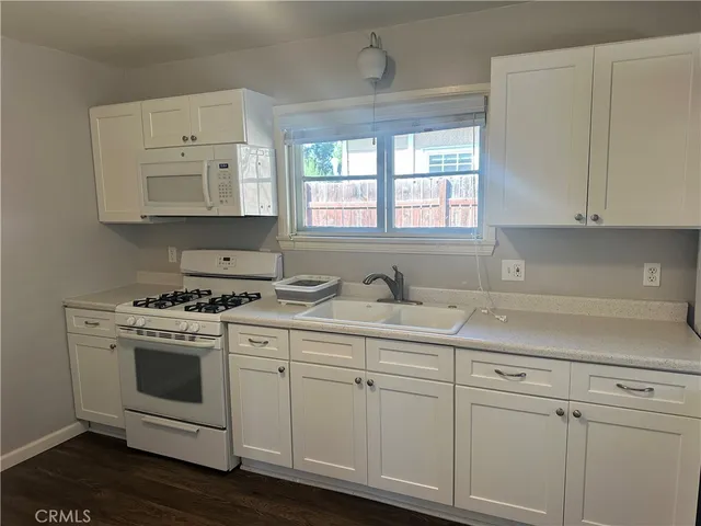 a kitchen with white cabinets and white appliances