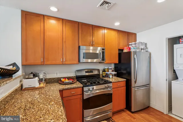 a kitchen with stainless steel appliances granite countertop a refrigerator stove and sink