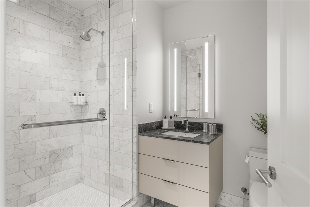 240 Devonshire Street, Unit 3701 Boston, MA 02110 - Photo 18 of 40 a bathroom with a granite countertop sink a mirror and a shower