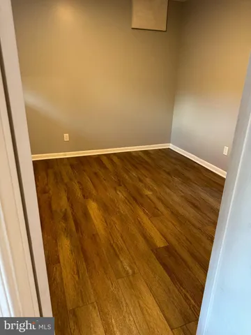 a view of an empty room with wooden floor and closet