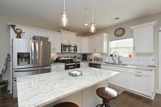 a kitchen with stainless steel appliances granite countertop a sink a stove and refrigerator