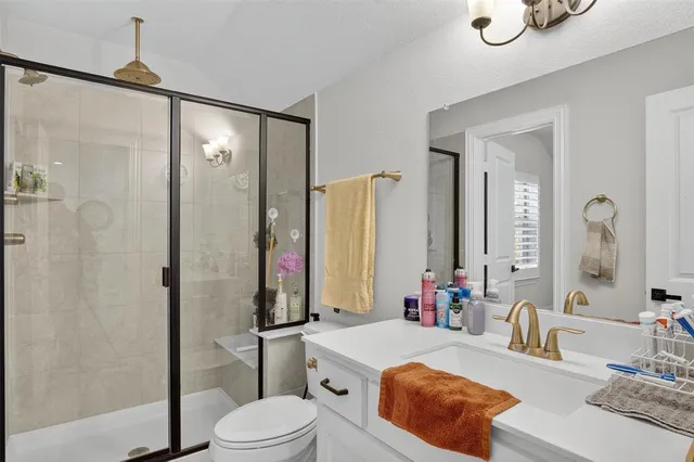 a bathroom with a granite countertop sink a toilet and shower
