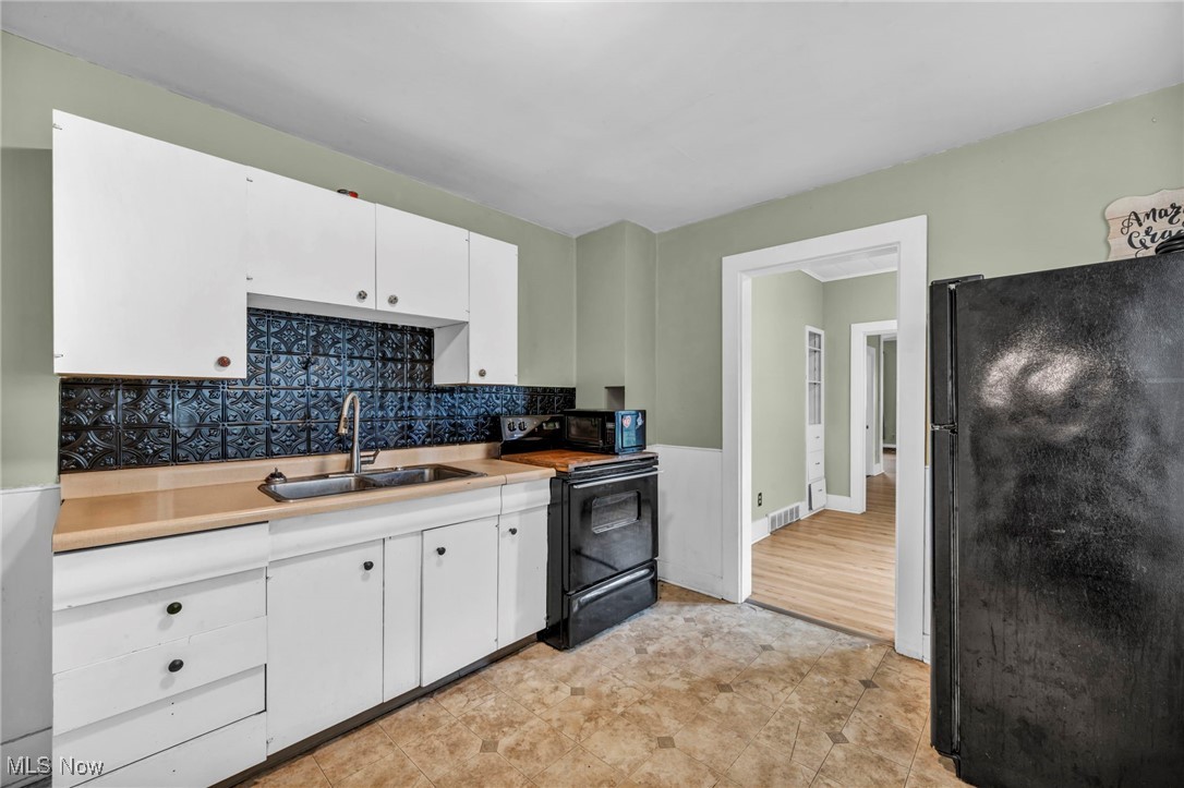 816 Perry Street Sandusky, OH 44870 - Photo 9 of 38 Kitchen with black appliances, light countertops, white cabinetry, and tasteful backsplash