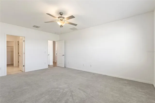 an empty room with a chandelier fan and windows