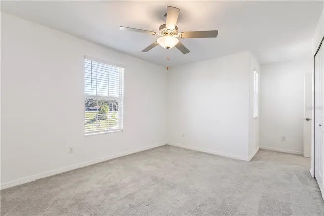 an empty room with a chandelier fan and windows
