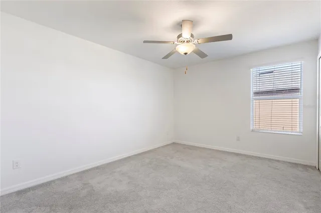 an empty room with windows and chandelier fan