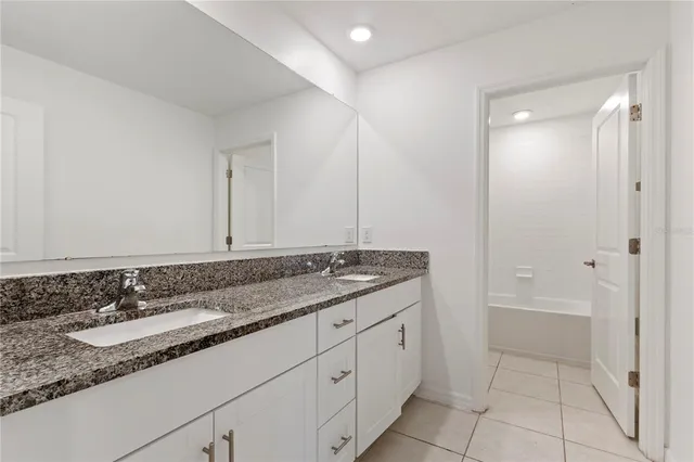 a bathroom with a granite countertop sink and a mirror