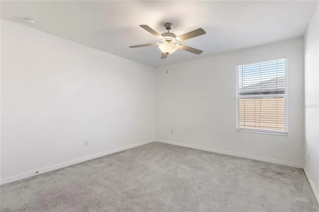 an empty room with a window and a fan