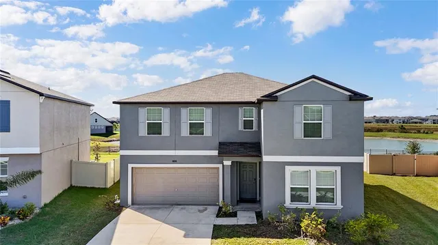 a view of a white house next to a yard with potted plants