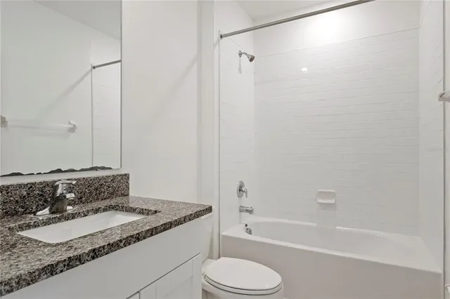 a bathroom with a granite countertop sink toilet and bathtub