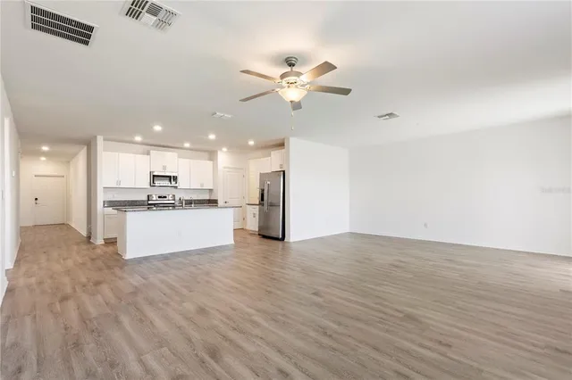 a view of kitchen with kitchen island wooden floor and a refrigerator