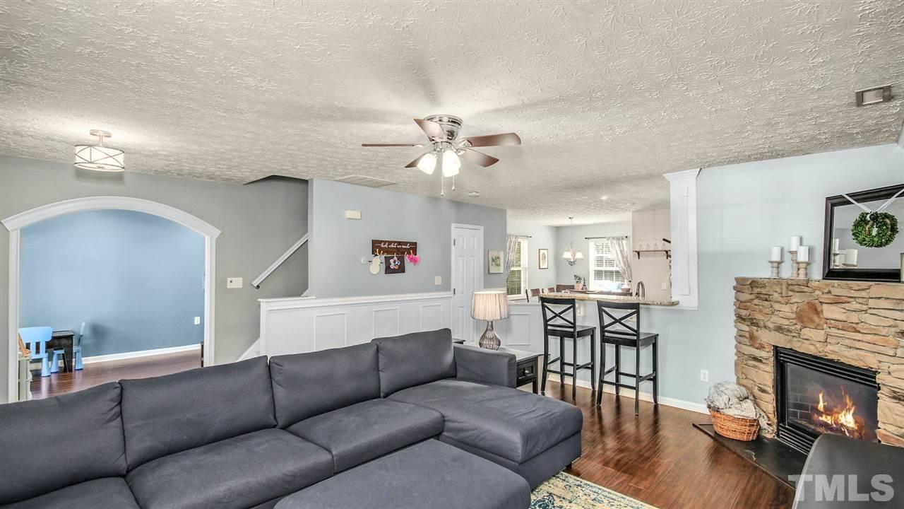 5720 Forest Point Road Raleigh, NC 27610 - Photo 4 of 22 a living room with furniture a fireplace and a chandelier