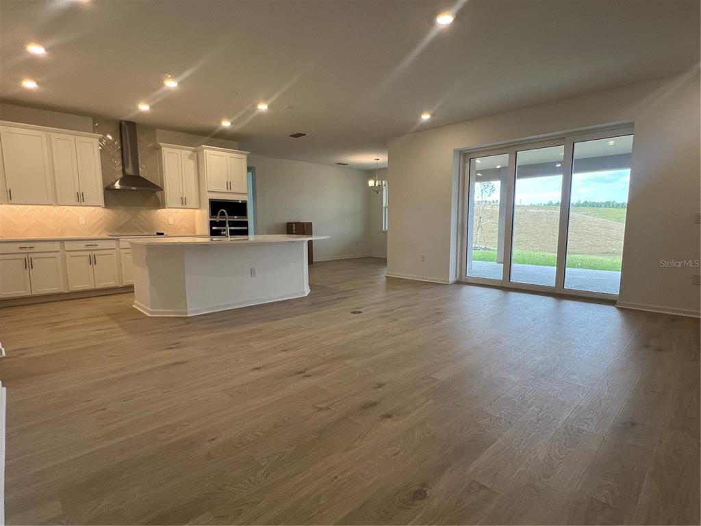 2075 Keystone Pass Boulevard Minneola, FL 34715 - Photo 6 of 27 a large white kitchen with kitchen island a sink wooden floor and a large window