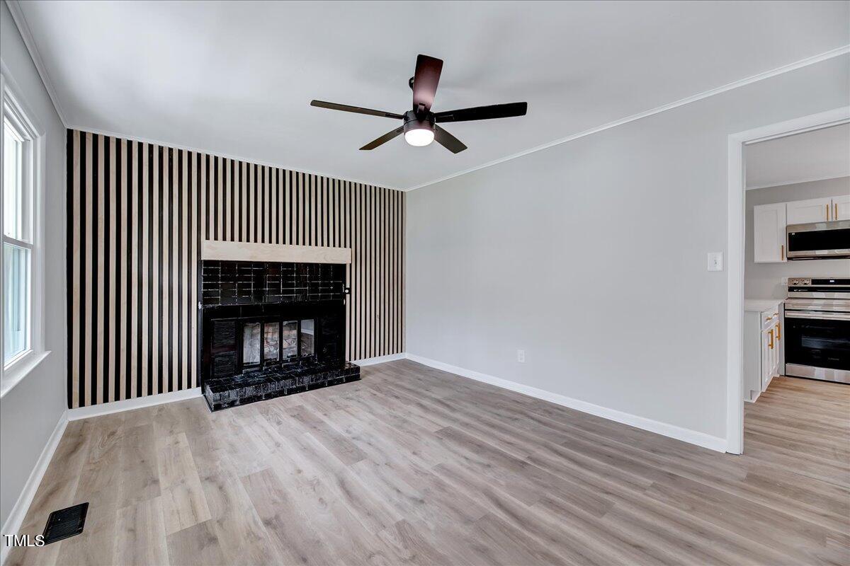 2808 Oak Ridge Court Raleigh, NC 27603 - Photo 8 of 43 a view of an empty room with wooden floor fireplace and a window