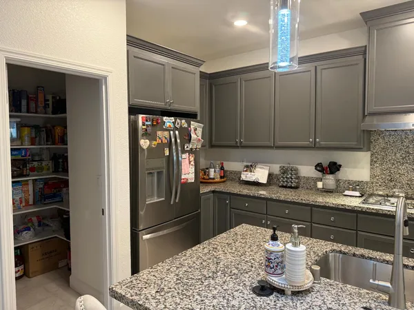 a kitchen with granite countertop a refrigerator and cabinets