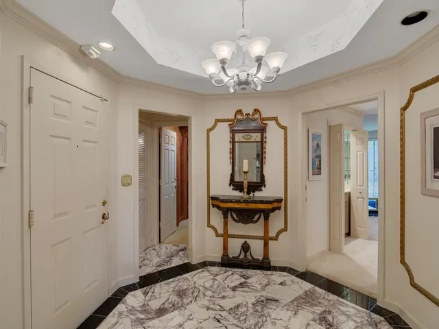 a view of a hallway with wooden floor and a chandelier