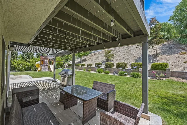 a patio with table and chairs and potted plants