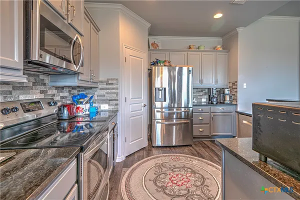 a kitchen with stainless steel appliances granite countertop a stove refrigerator sink and microwave