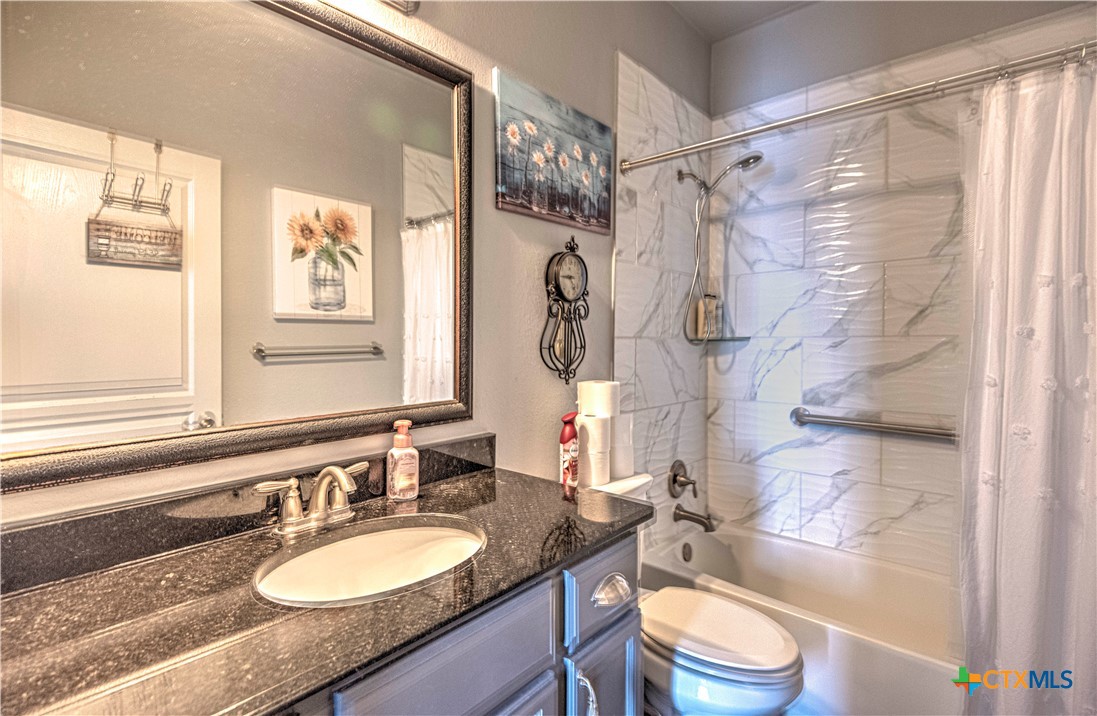 504 Coventry Drive Temple, TX 76502 - Photo 22 of 30 a bathroom with a granite countertop sink toilet a mirror a bathtub and shower