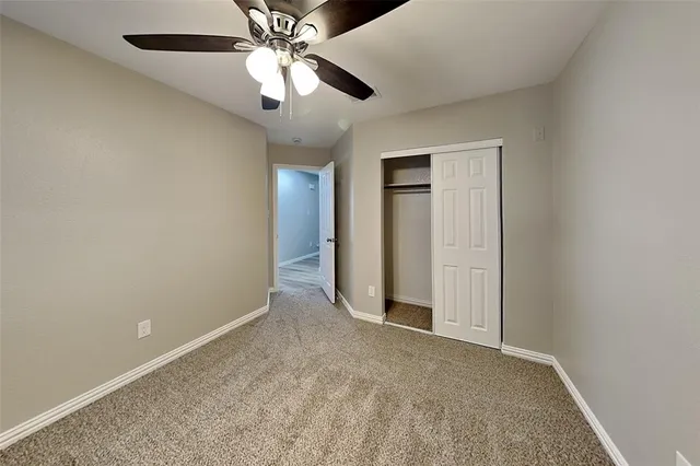 an empty room with closet and a chandelier fan