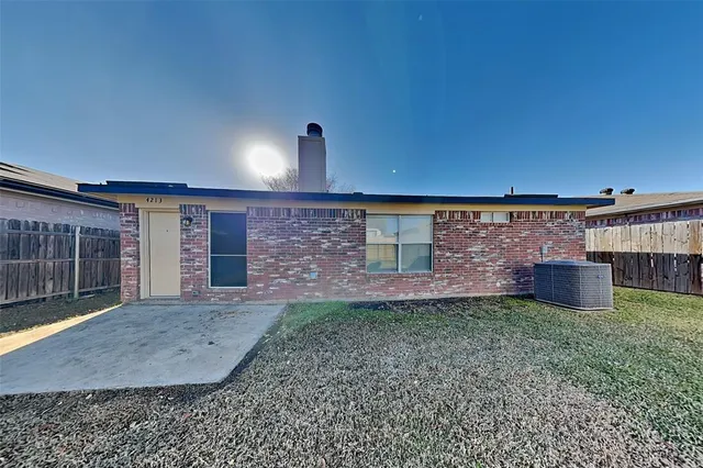 a view of a backyard with plants and brick wall