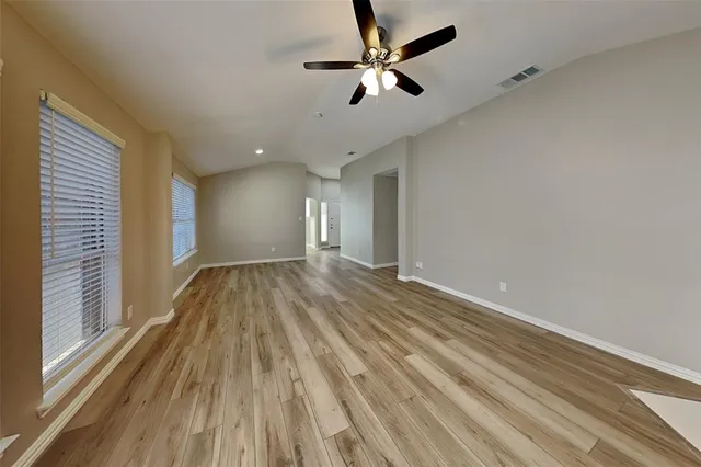 a view of empty room with wooden floor and fan