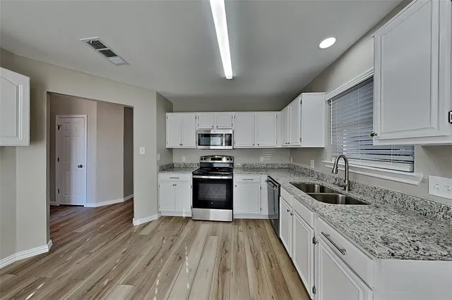a kitchen with granite countertop a sink wooden floor and stainless steel appliances