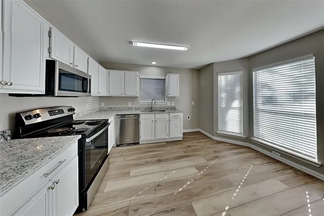 a kitchen with stainless steel appliances granite countertop a stove a sink and a microwave