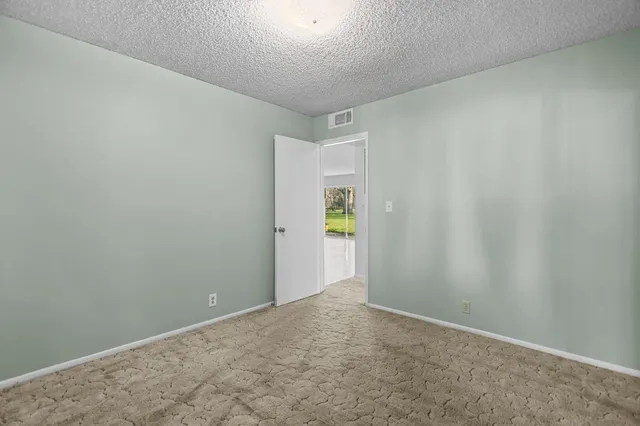 a view of a yard with a house and trees in the background