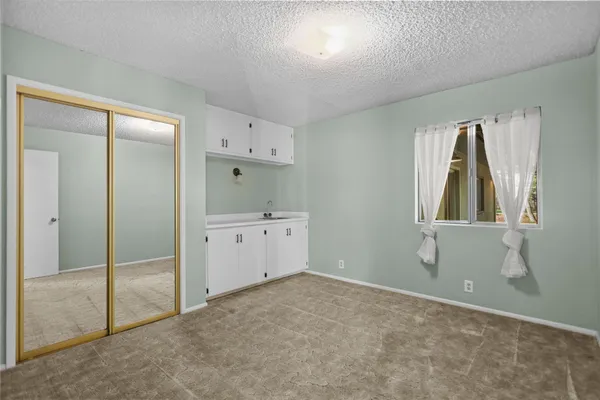 a view of a yard with a house and trees in the background