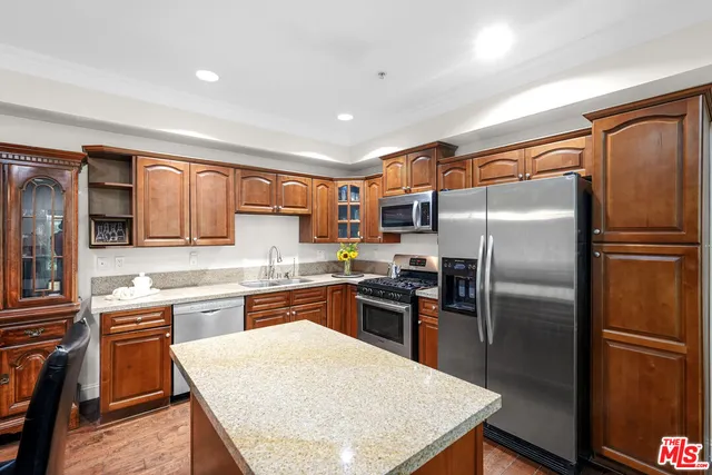 a kitchen with stainless steel appliances granite countertop a refrigerator a stove top oven a sink dishwasher and white cabinets with wooden floor