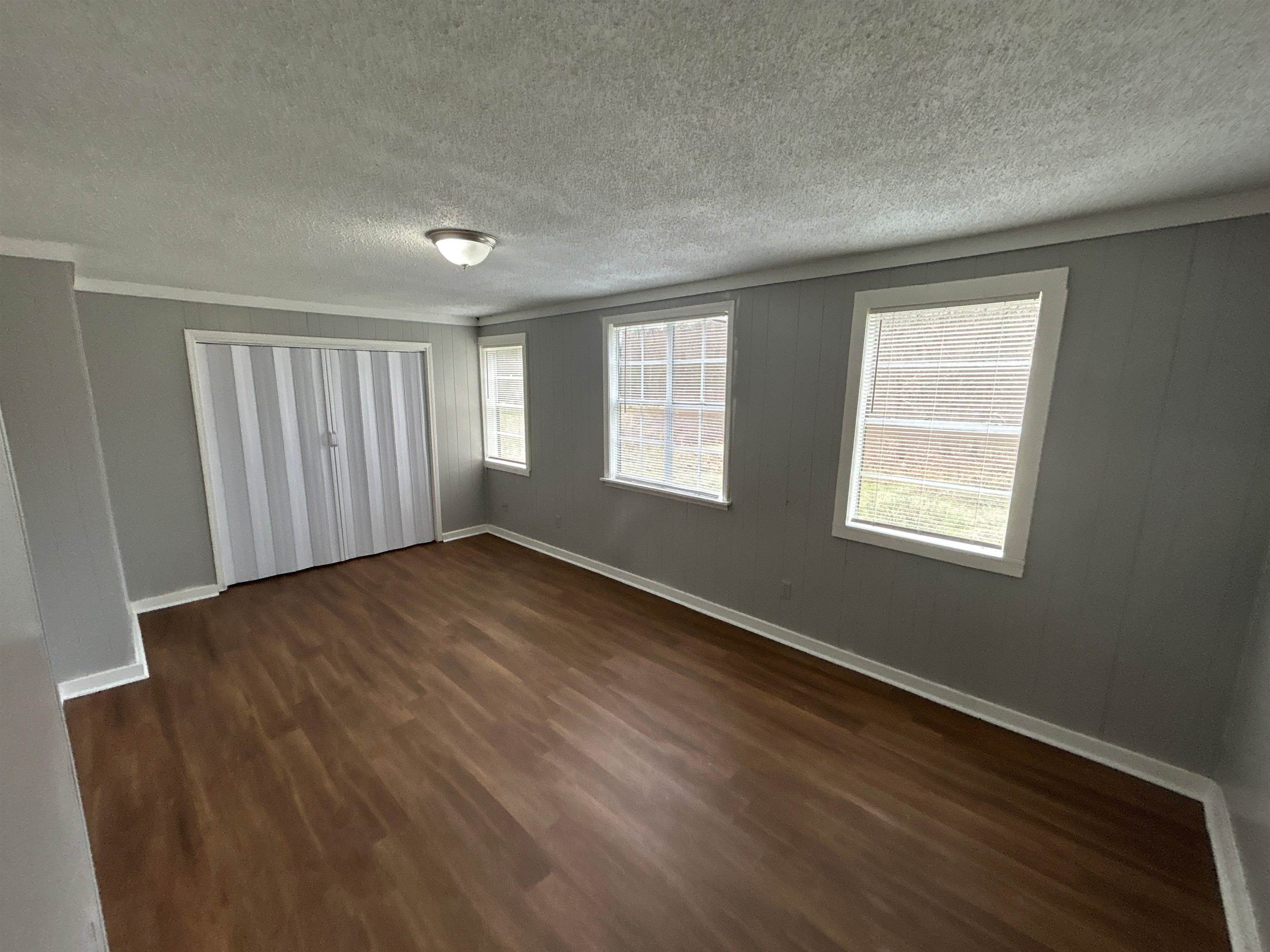 3447 Cook Road Memphis, TN 38109 - Photo 2 of 7 Unfurnished bedroom with a textured ceiling, dark wood-type flooring, a closet, and ornamental molding
