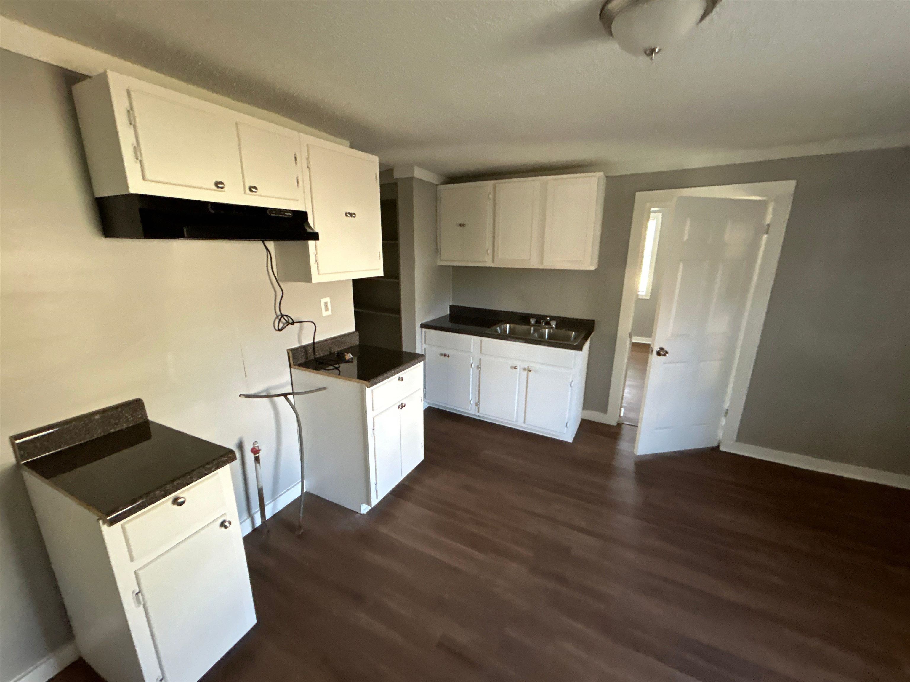 3447 Cook Road Memphis, TN 38109 - Photo 4 of 7 Kitchen with dark countertops, white cabinets, and dark wood-style flooring