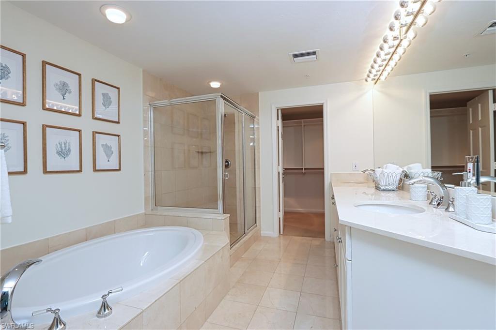 60 Seagate Drive, Unit 704 Naples, FL 34103 - Photo 14 of 28 a bathroom with a tub a sink and mirror