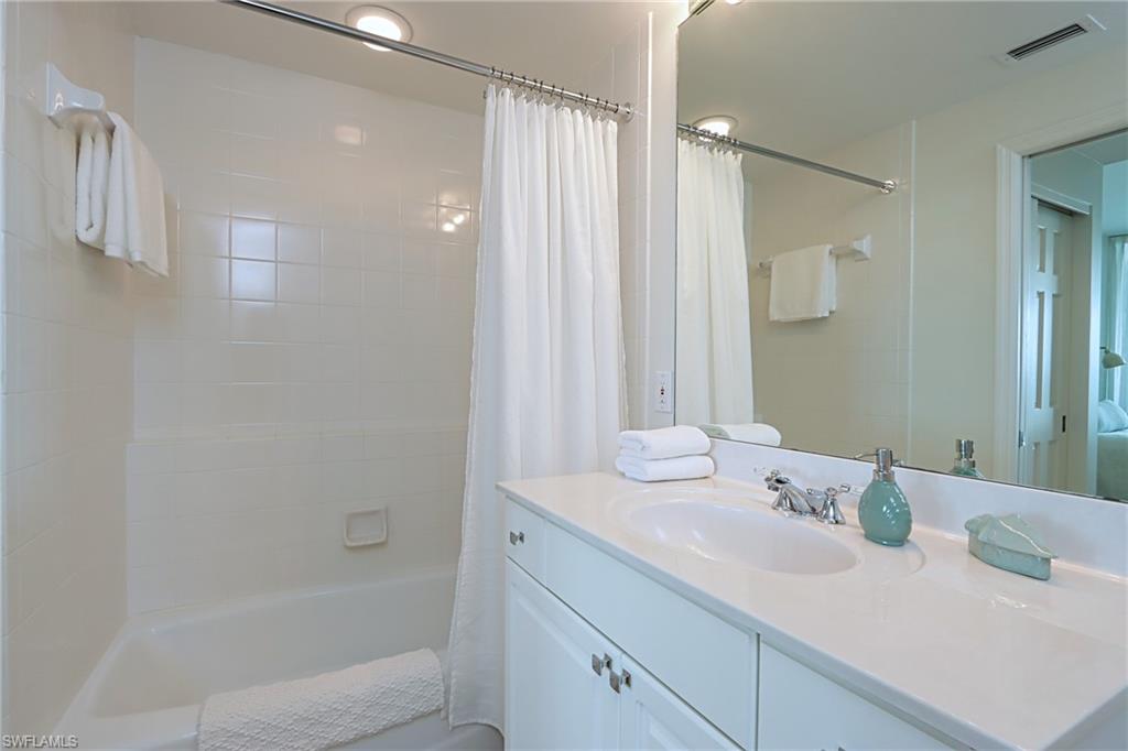 60 Seagate Drive, Unit 704 Naples, FL 34103 - Photo 18 of 28 a bathroom with a granite countertop sink and a mirror