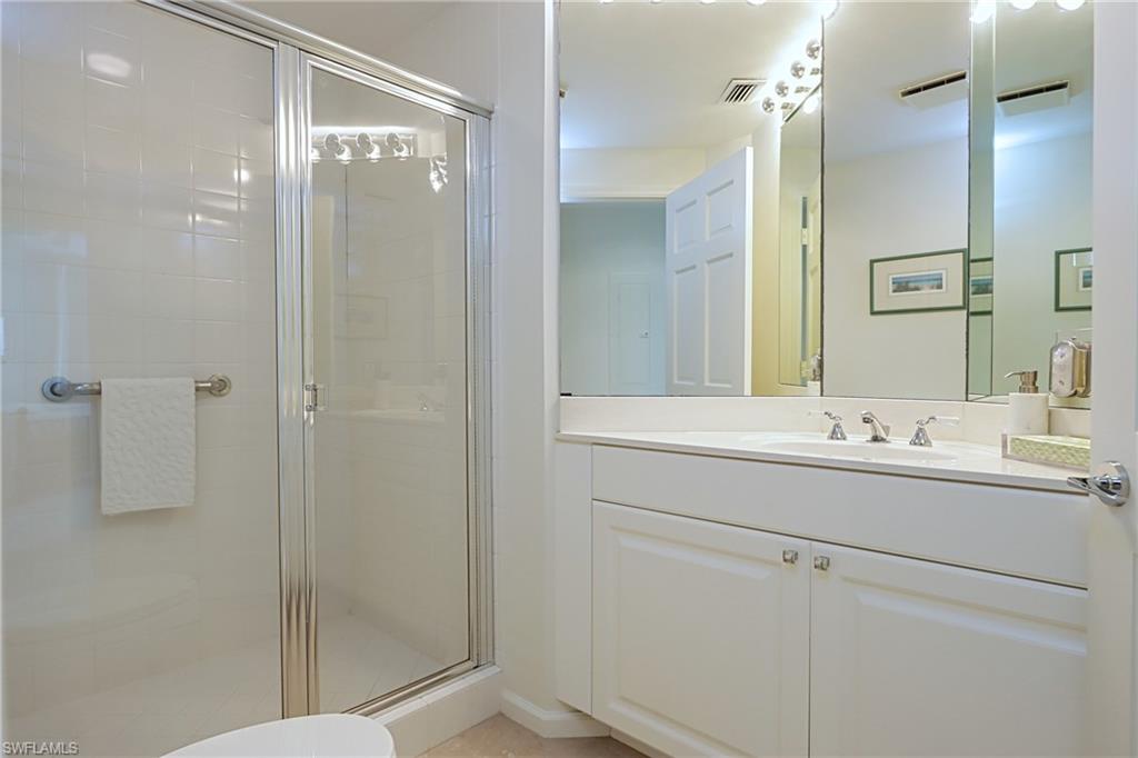 60 Seagate Drive, Unit 704 Naples, FL 34103 - Photo 21 of 28 a bathroom with a shower sink and mirror