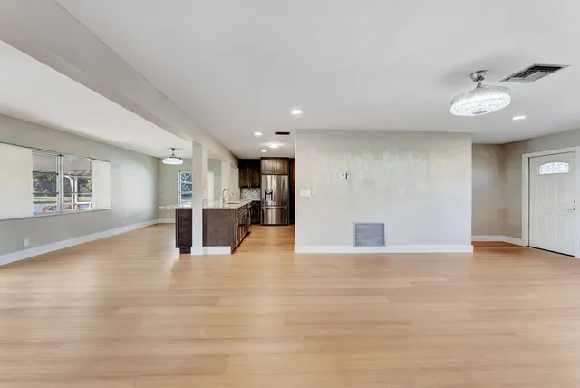 a view of an empty room with a window and wooden floor