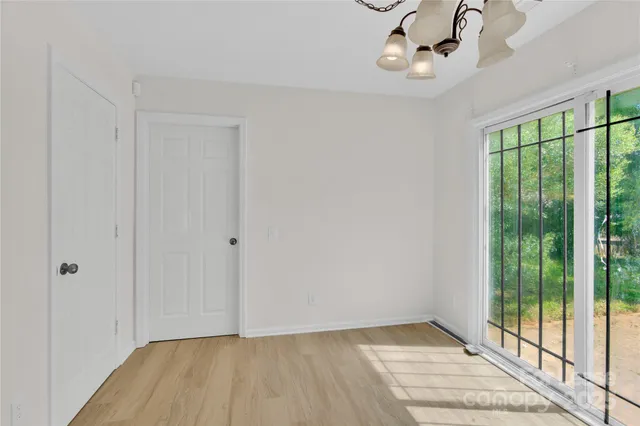 a view of an empty room with wooden floor and fan