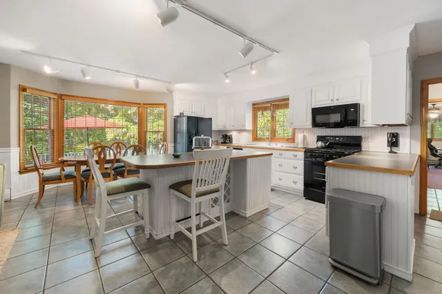 a kitchen with stainless steel appliances granite countertop a stove top oven a sink dishwasher a dining table and chairs with wooden floor