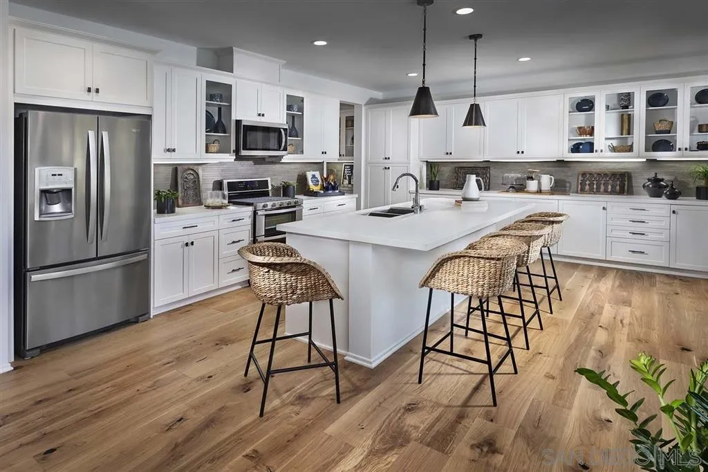 24384 Crooked Trail Menifee, CA 92584 - Photo 2 of 21 a kitchen with stainless steel appliances kitchen island granite countertop a refrigerator a stove a microwave oven a sink with island and chairs with wooden floor