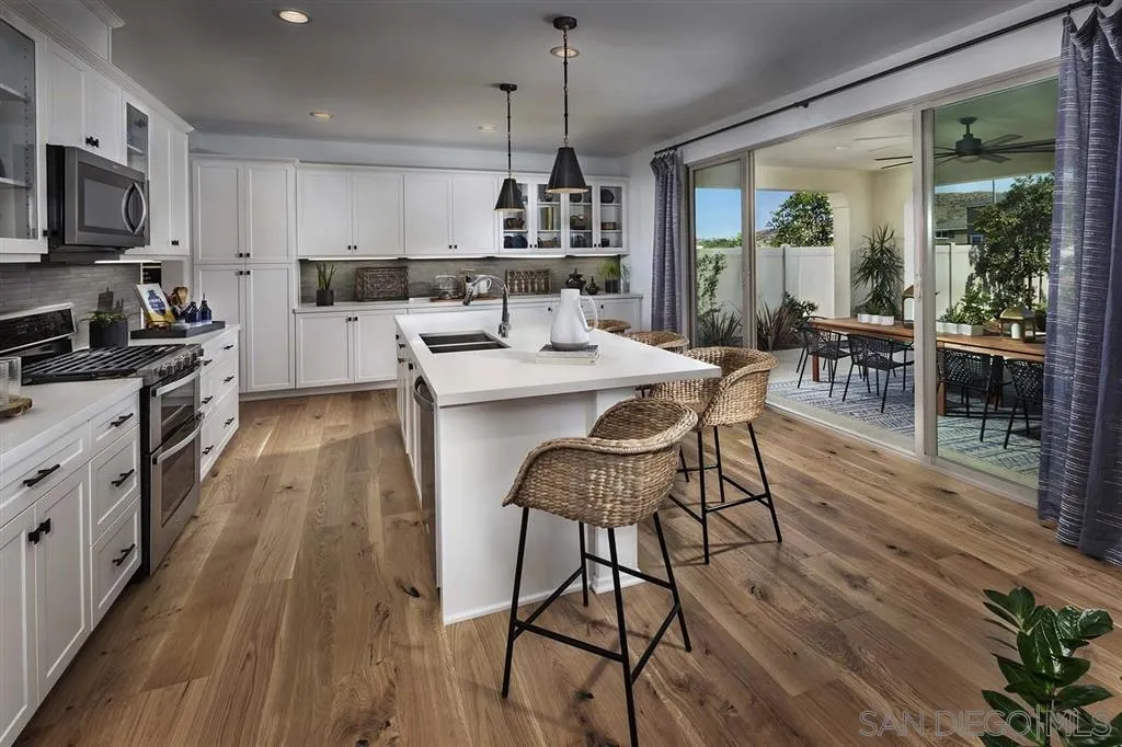 24384 Crooked Trail Menifee, CA 92584 - Photo 3 of 21 a kitchen with stainless steel appliances a dining table chairs stove refrigerator and cabinets