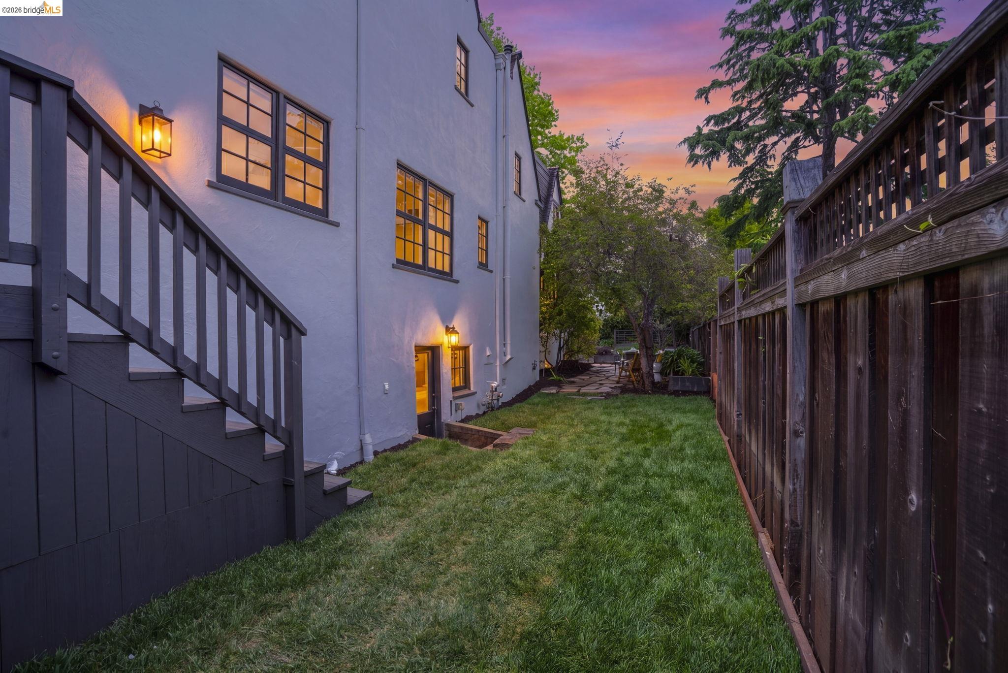 1087 Hubert Road Oakland, CA 94610 - Photo 37 of 67 Expansive rear yard featuring a manicured lawn, dark wood privacy fencing, and a stucco exterior