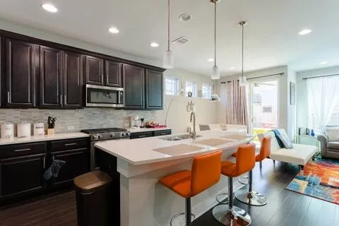 a kitchen with stainless steel appliances granite countertop a sink a stove a refrigerator cabinets and chairs