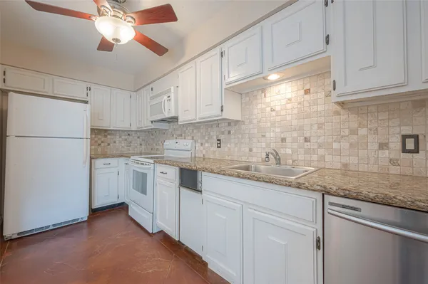 a kitchen with granite countertop cabinets stainless steel appliances a sink and a window
